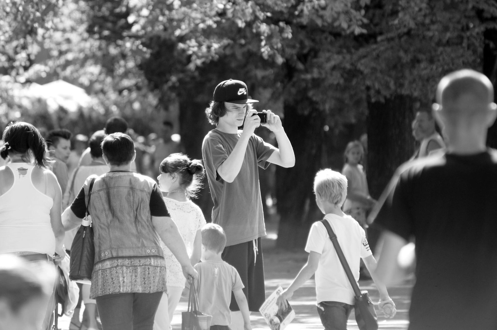 Black and white photo capturing diverse group of people walking in an urban park.